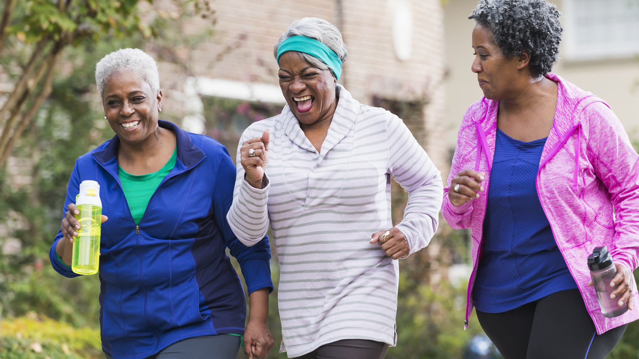 Tres mujeres mayores caminando al aire libre con ropa deportiva.