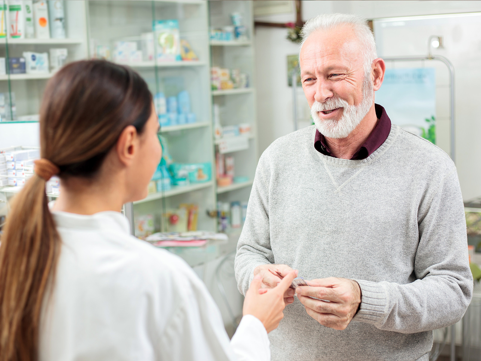 Hombre adulto en una farmacia pagando por su medicamento.