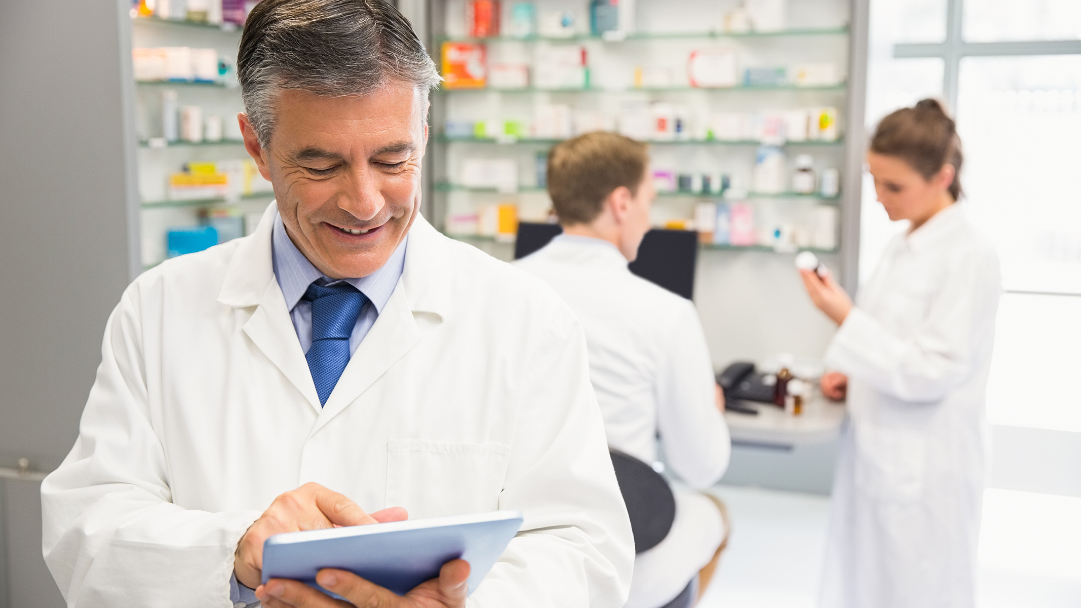 Male pharmacist using a tablet in a pharmacy.