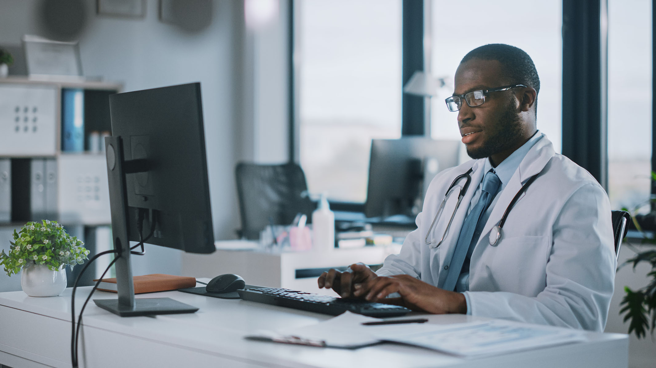 Healthcare professional at desk working on a computer.