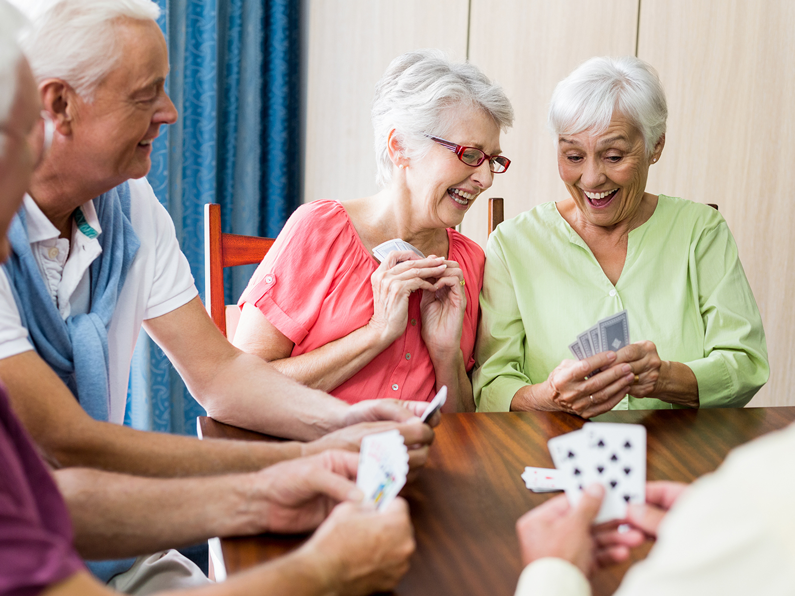 Group of seniors around a table playing cards