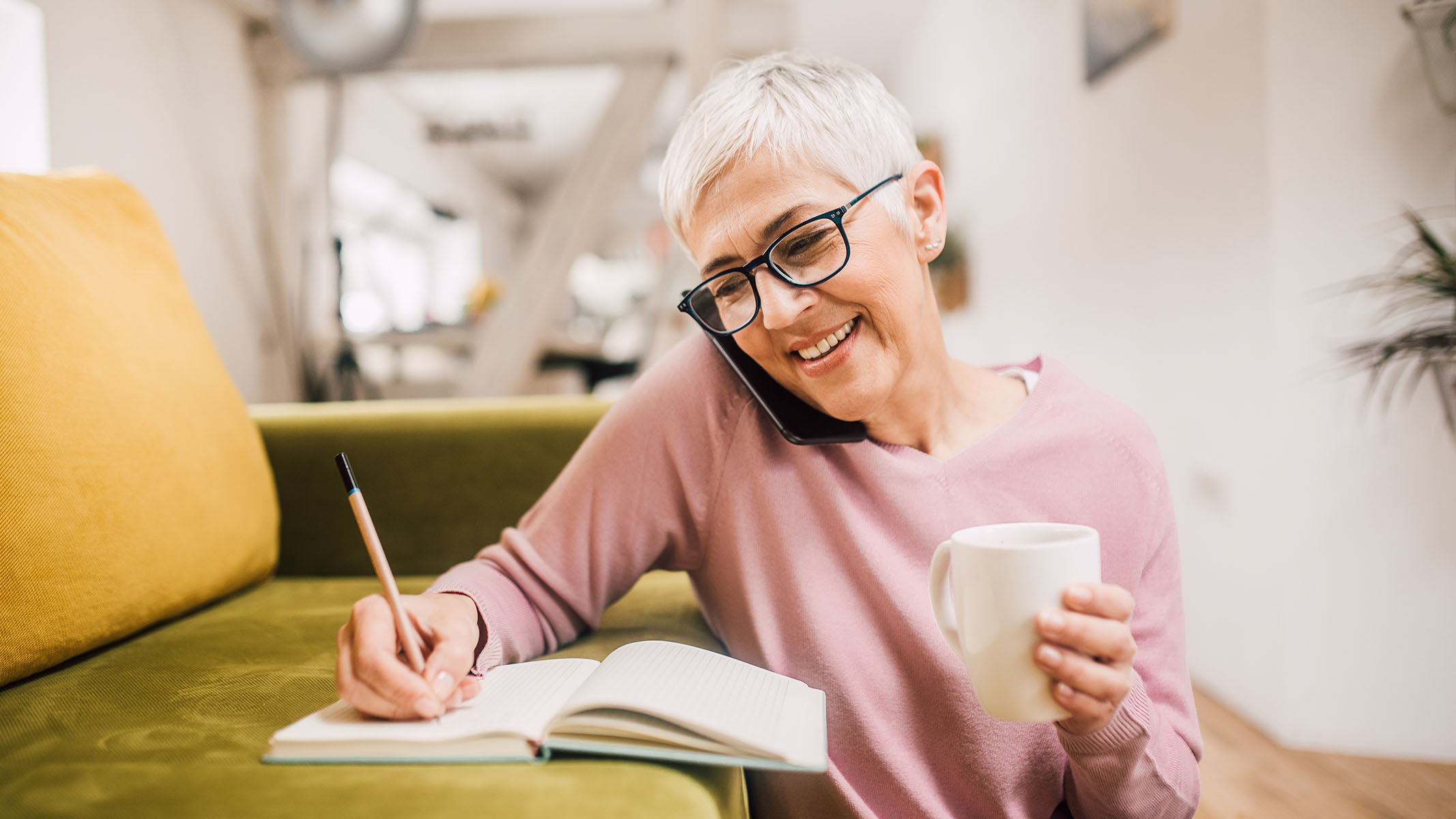 Senior woman taking notes while talking on the phone