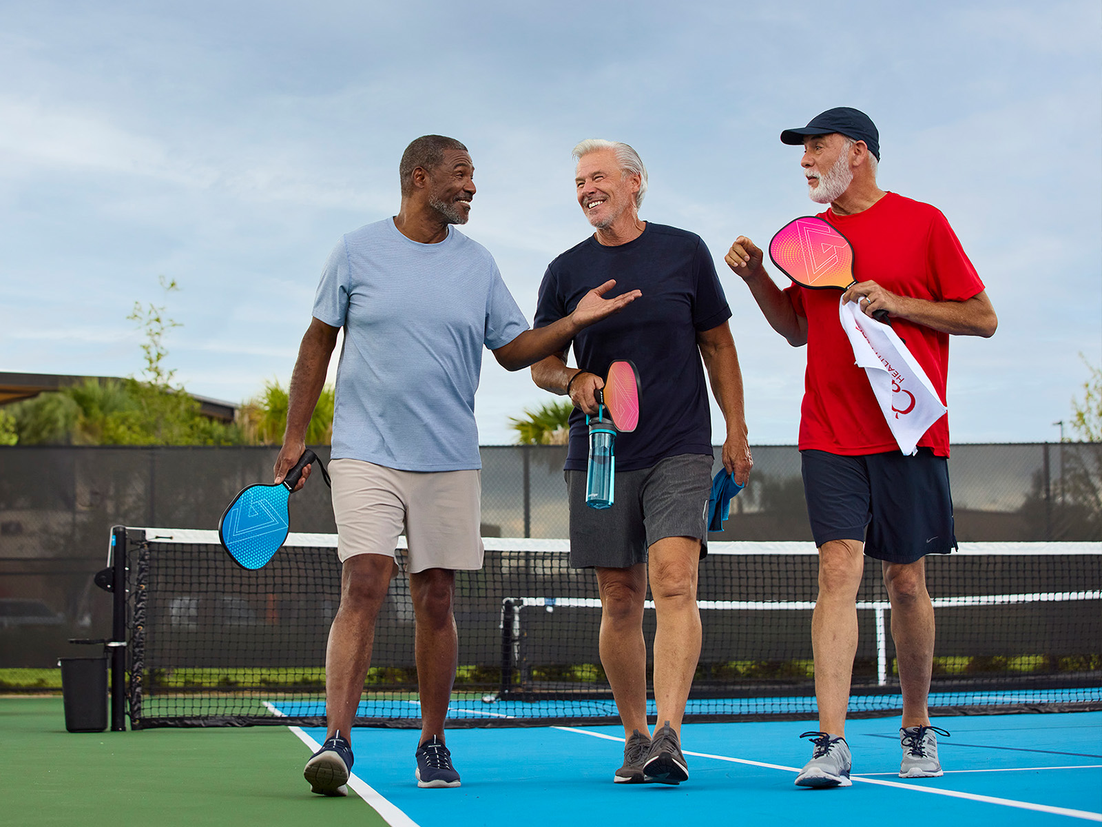 Grupo de jugadores de pickleball de la tercera edad hablando después de un partido.