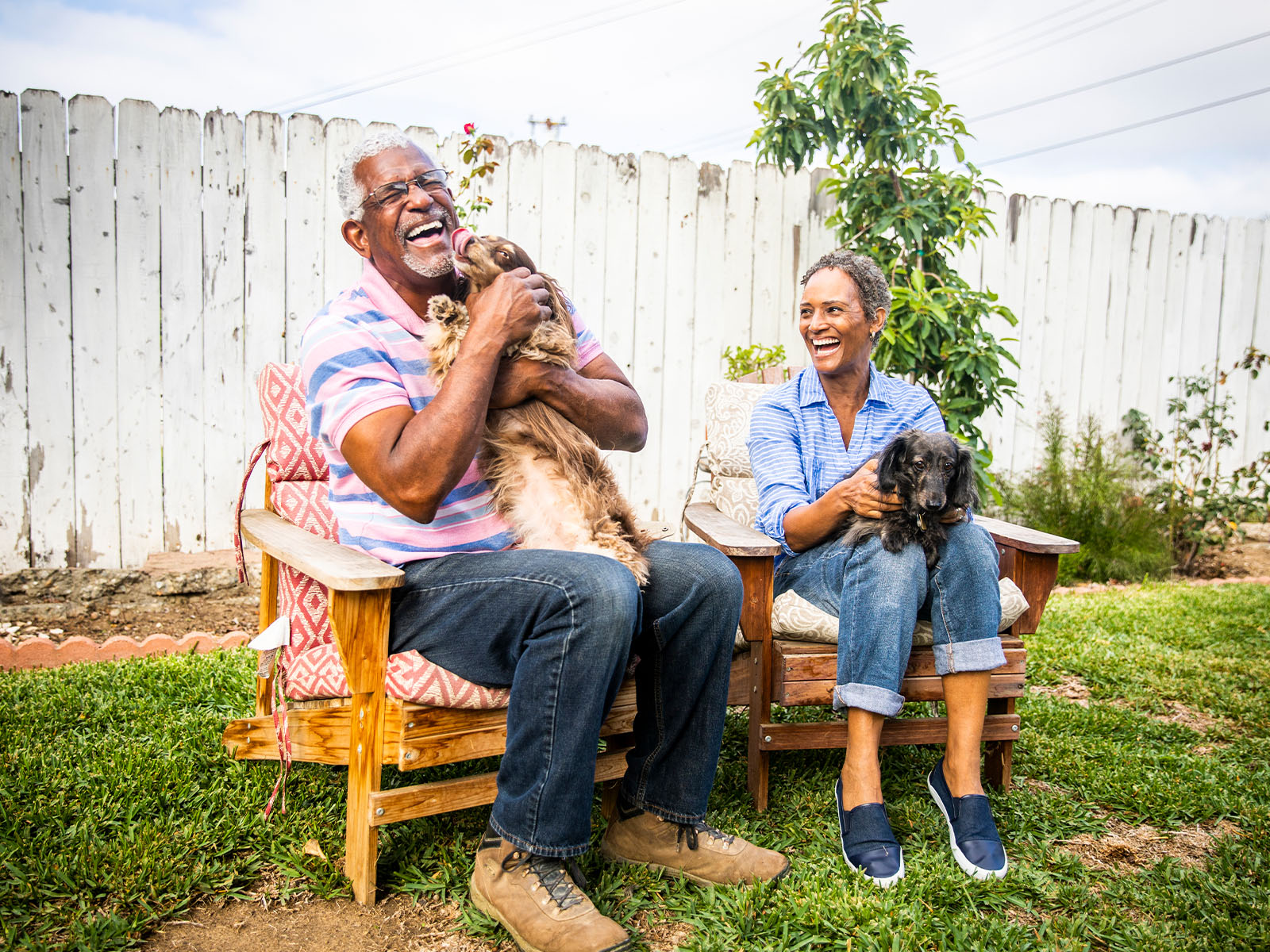 Una pareja de personas mayores jugando al aire libre con sus perros.