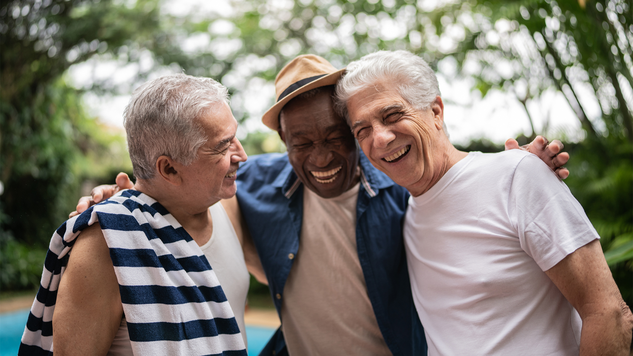  Three senior men smiling by the pool.