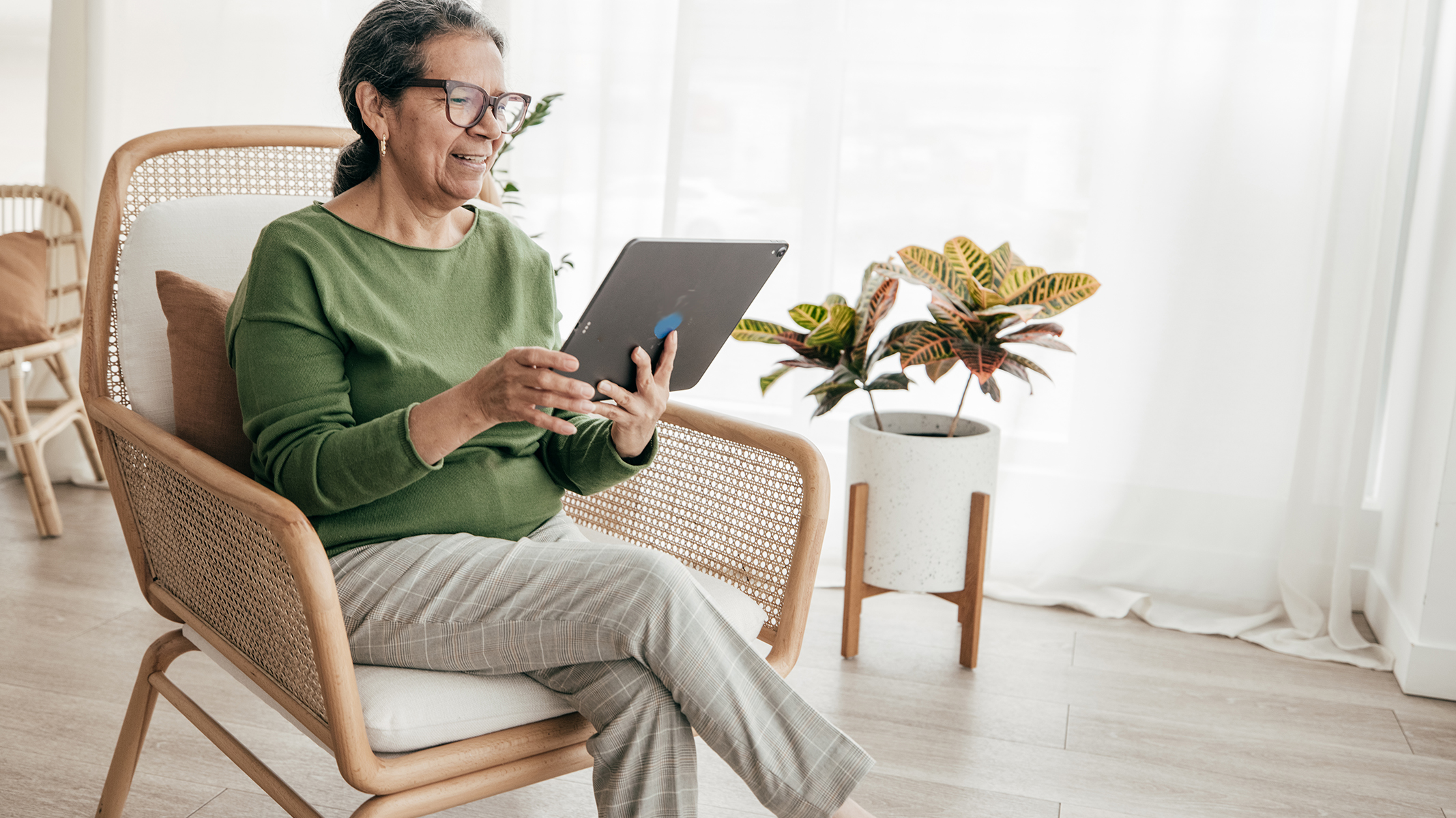  Senior woman sitting looking at tablet device.