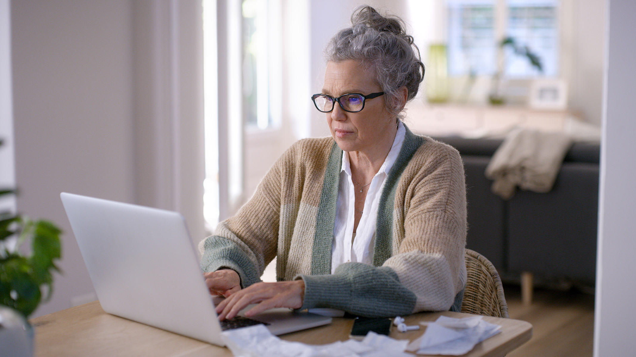 Mujer mayor trabajando en un computador portátil sentada a la mesa